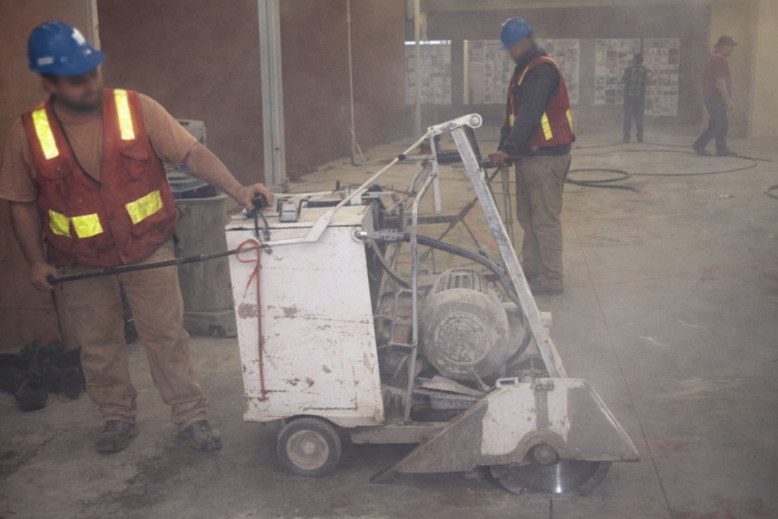 Byggarbetare som använder en golvsåg för betongkapning inomhus.